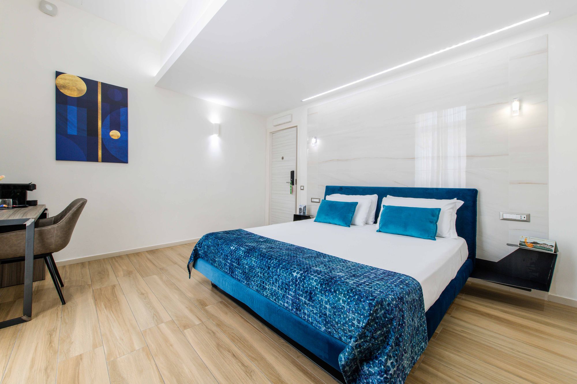 Vista d'insieme della camera con testiera blu velluto e pavimento in legno - Municipio Luxury Suite Napoli, foto 4