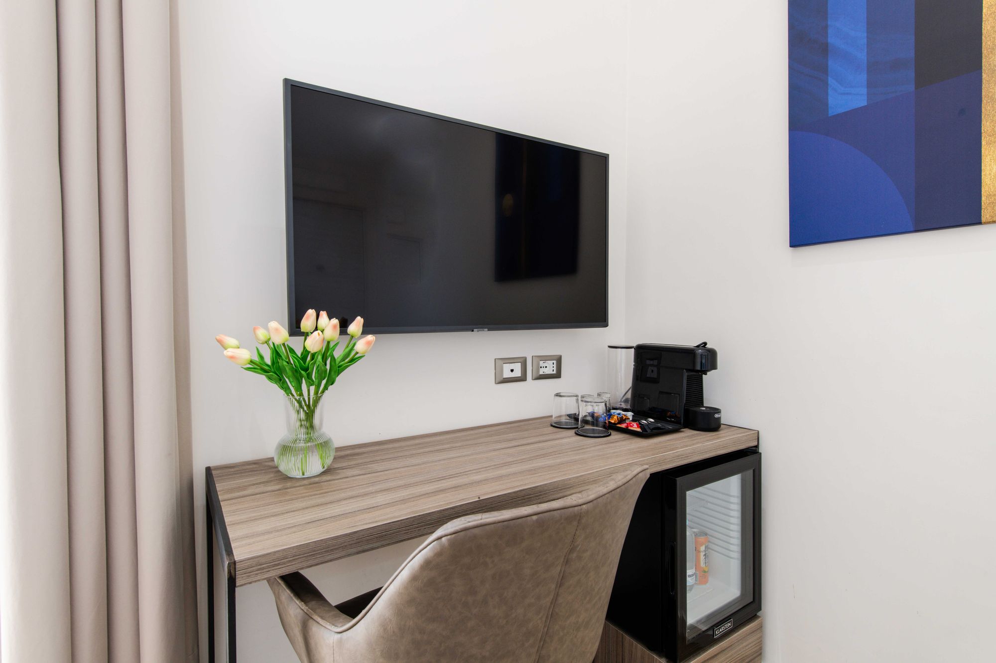 Scrivania con TV a parete, angolo caffè e vaso di tulipani, camera B&B Napoli - Municipio Luxury Suite Napoli, foto 5