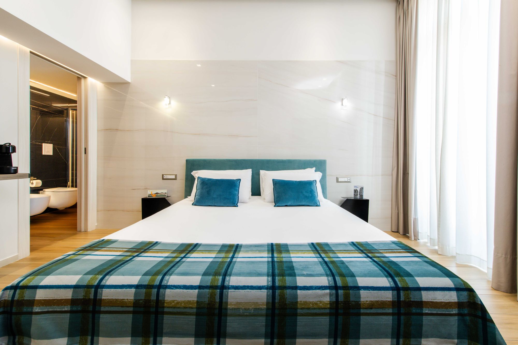 Letto con testiera verde acqua, cuscini turchesi e plaid a quadri, camera B&B Napoli