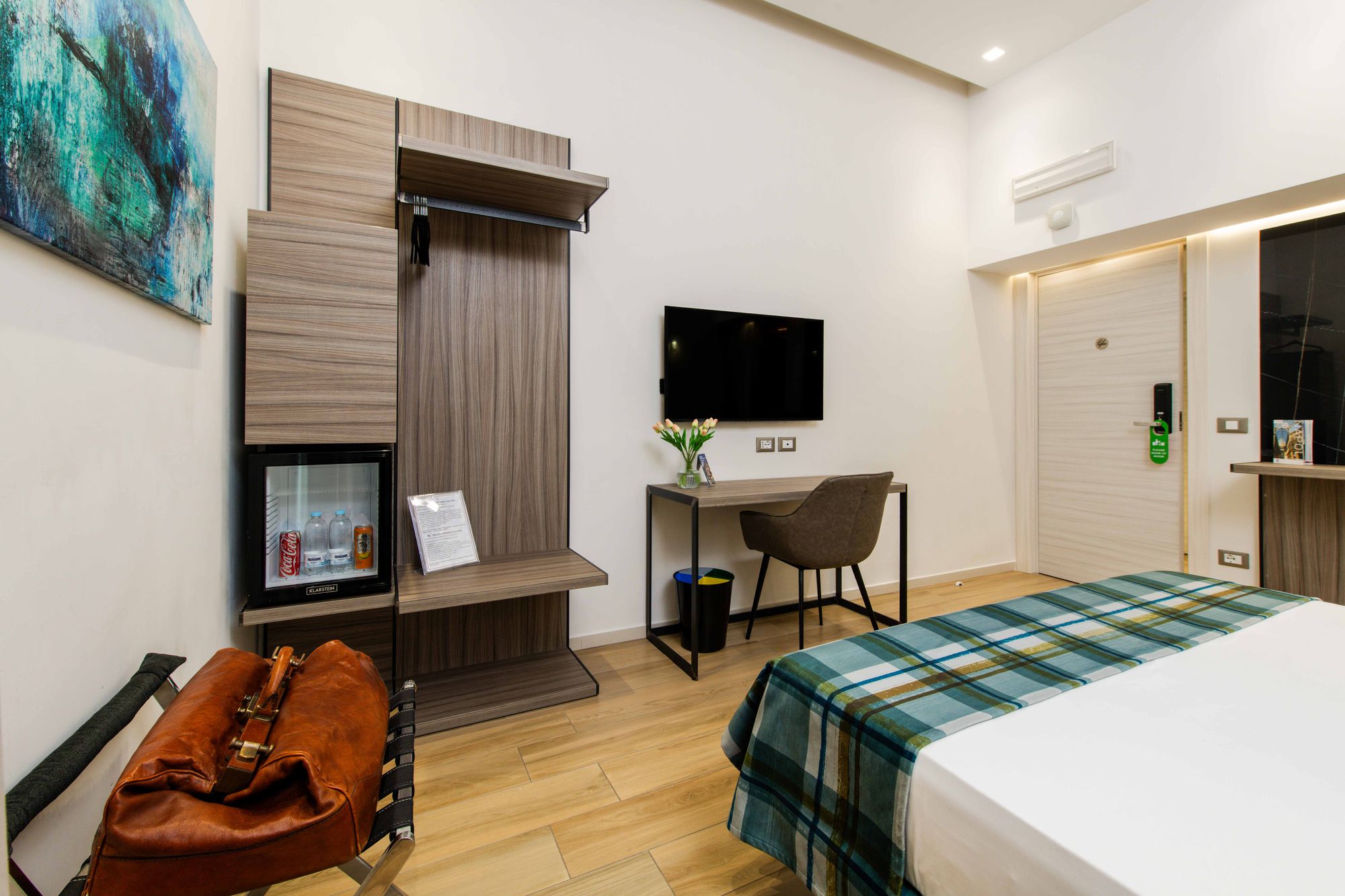 Armadio con minibar e scrivania con TV a parete, valigia in pelle, B&B Piazza Municipio Napoli