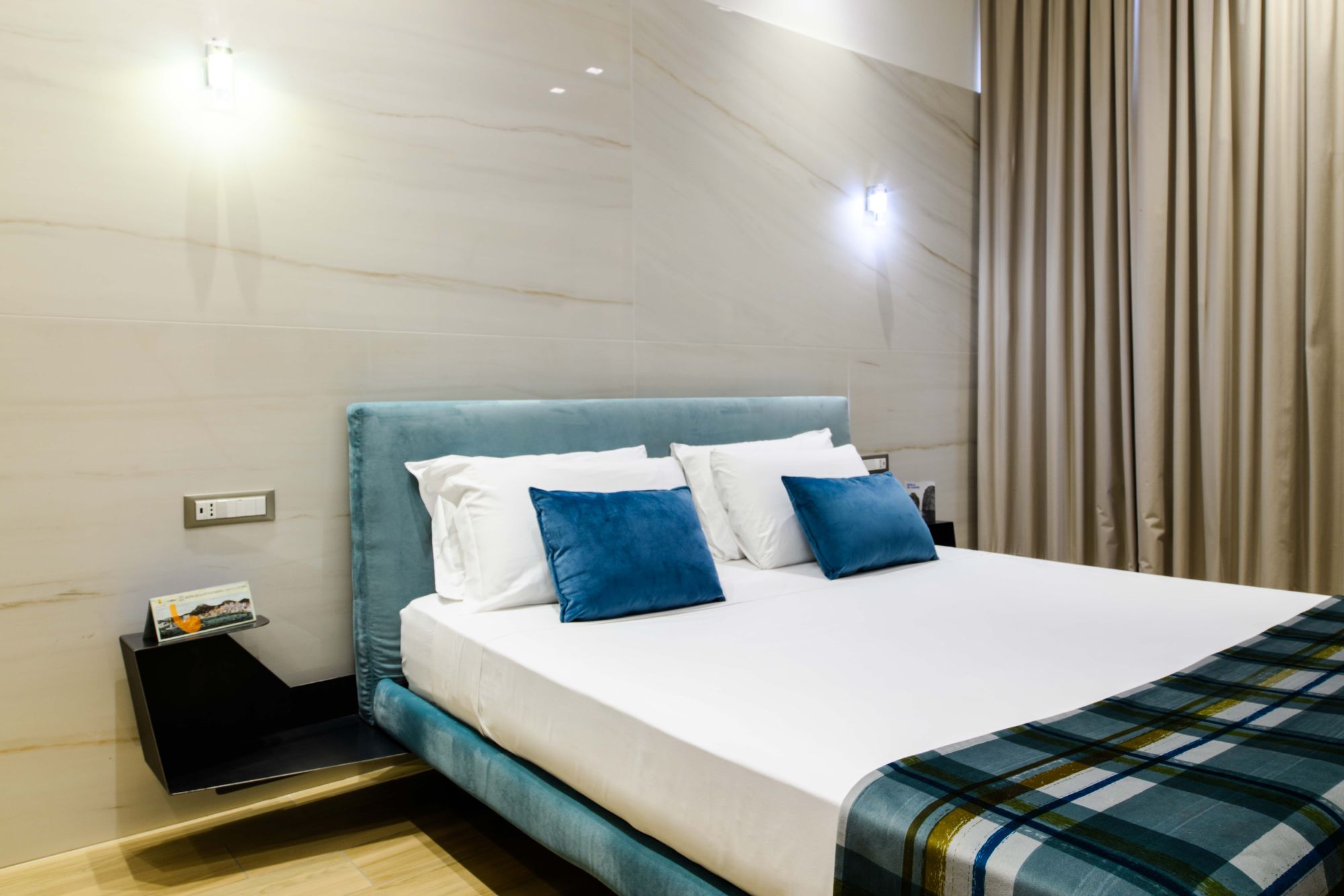 Letto matrimoniale con testiera turchese, cuscini blu e plaid a quadri