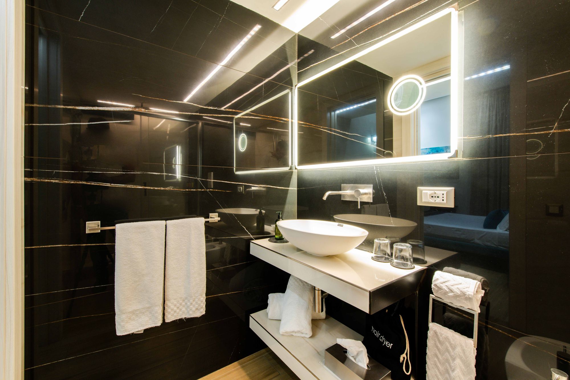 Lavabo con specchio a LED e asciugamani in marmo nero, camera Piazza Municipio Napoli