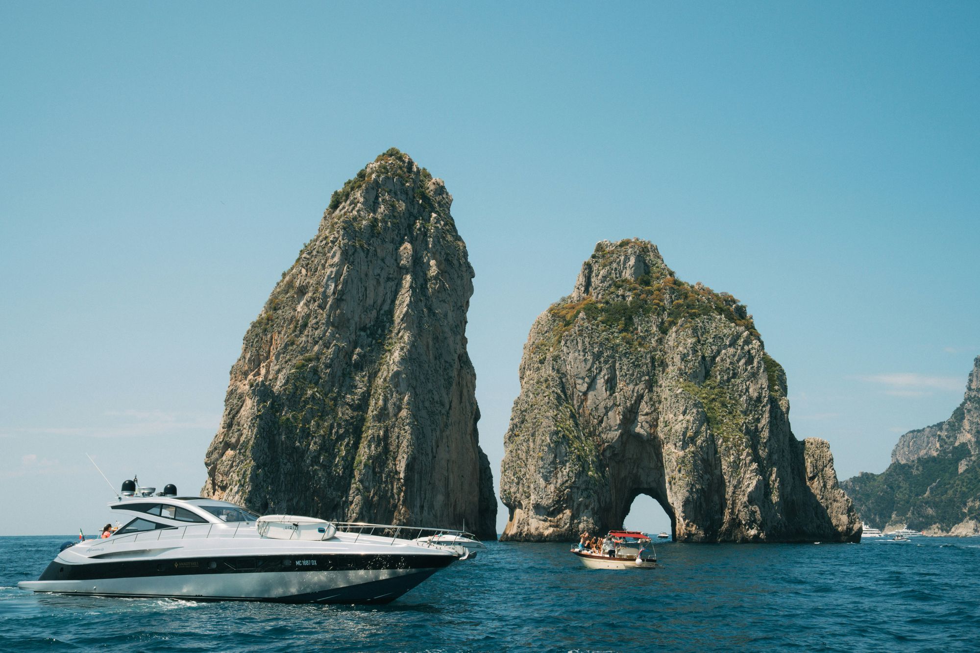 Barca privata al largo dei Faraglioni di Capri durante un tour in barca da Napoli