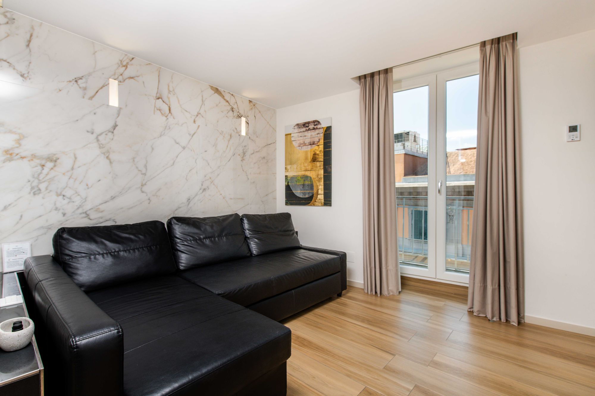 Zona living della suite con sauna, divano in pelle nera e parete in marmo bianco, B&B Napoli centro