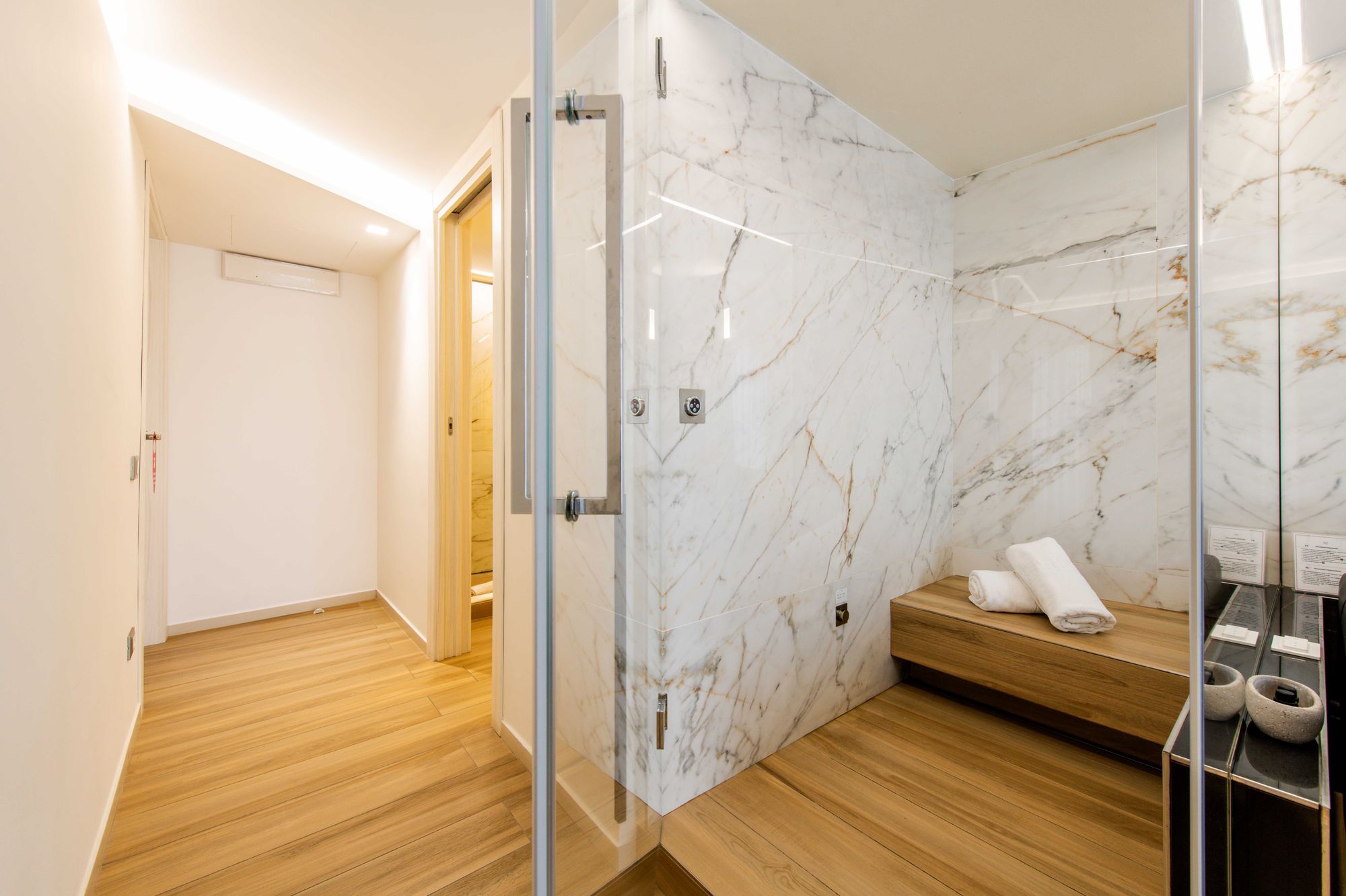 Sauna privata in marmo con panca in legno e box doccia in vetro, suite Piazza Municipio Napoli