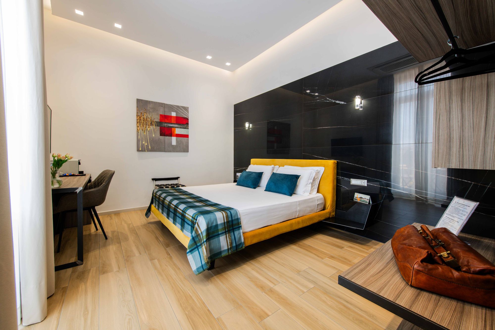 Letto matrimoniale con testiera gialla, cuscini turchesi e plaid a righe, suite con sauna Napoli