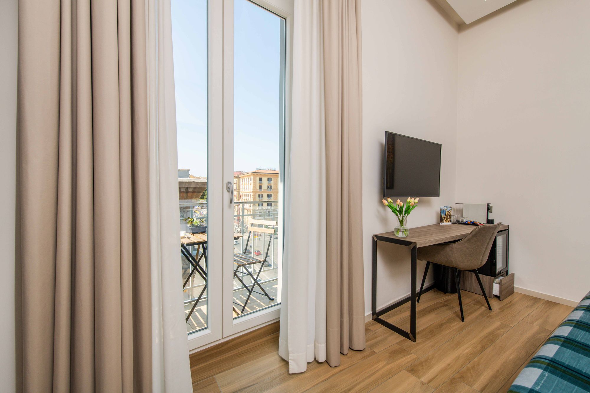 Scrivania con TV a parete, vaso di tulipani e accesso al balcone, suite con sauna Piazza Municipio Napoli