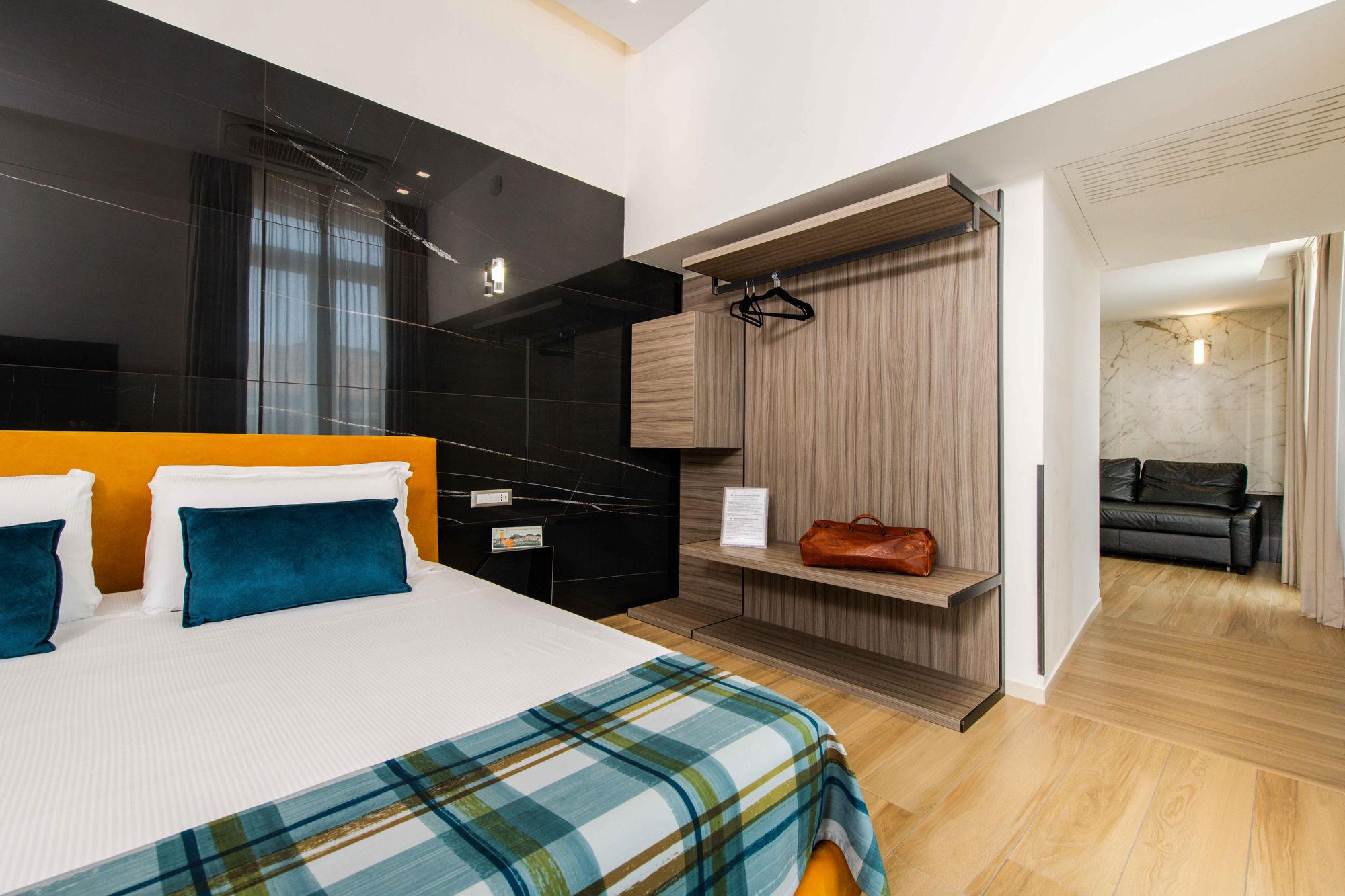 Letto con testiera gialla, cuscino turchese e armadio a giorno con valigia in pelle, suite con sauna