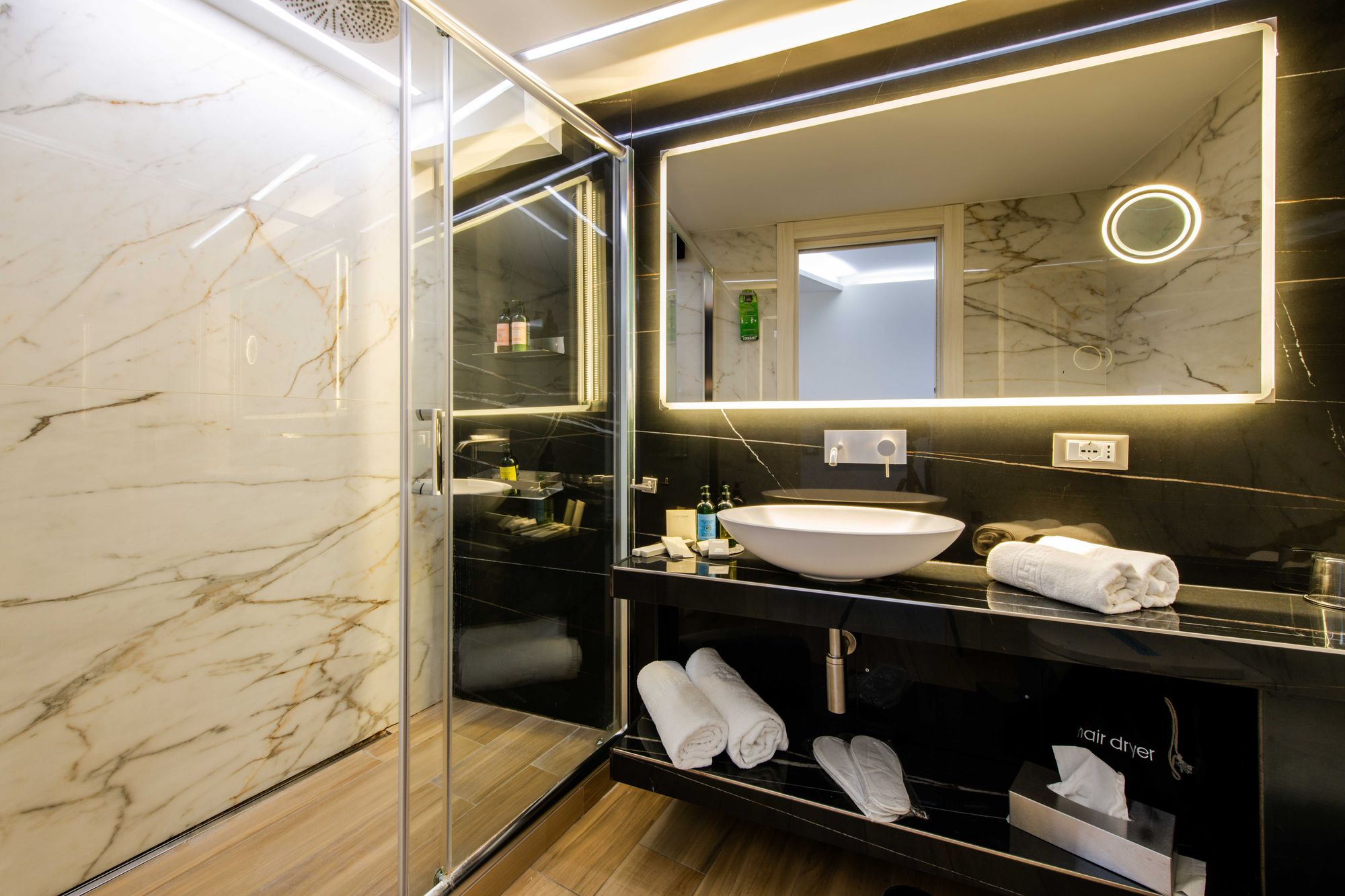Dettaglio pareti in marmo beige e specchiature del bagno, suite Piazza Municipio Napoli