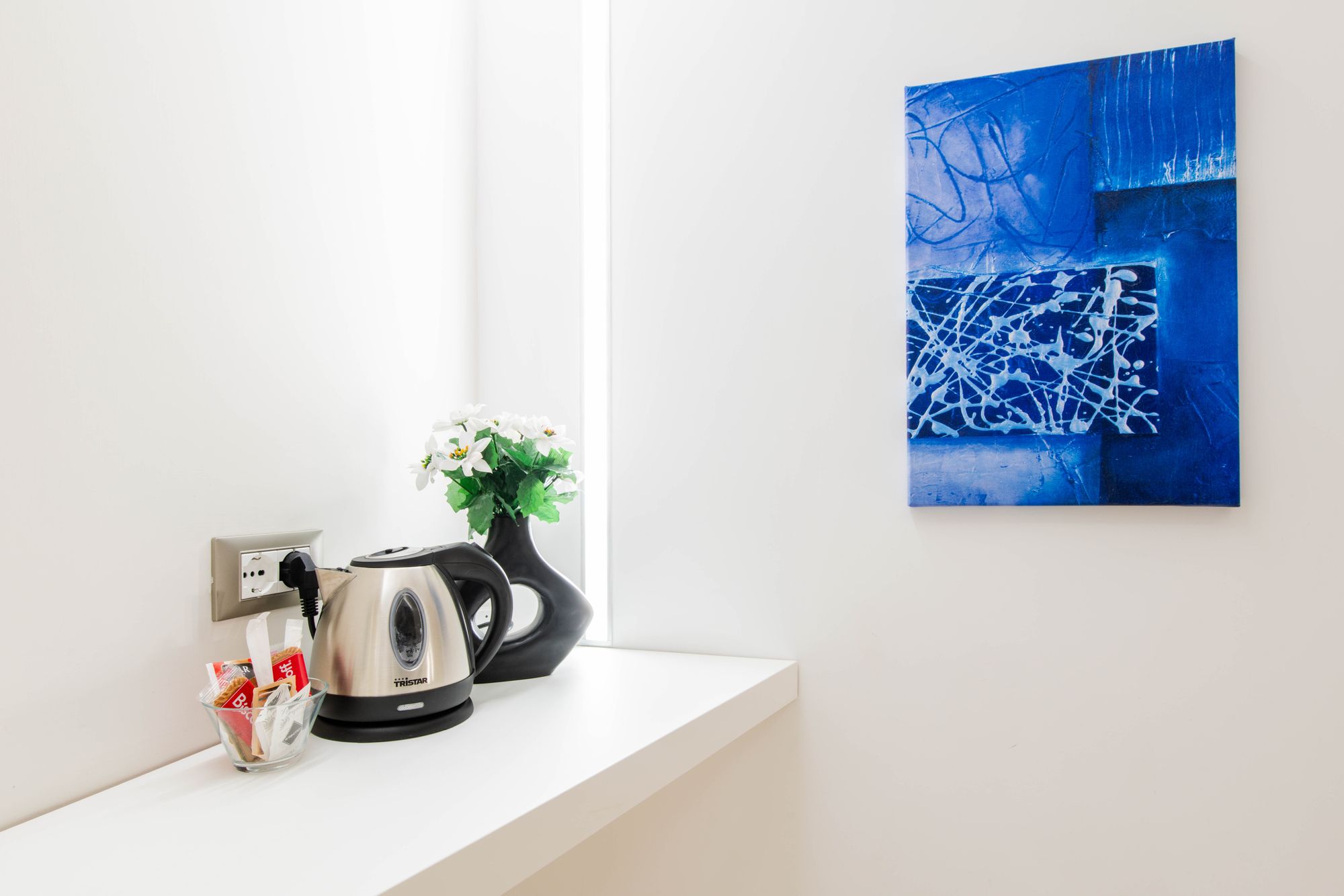 Angolo tè con bollitore, fiori e quadro astratto blu, dettaglio camera Municipio Luxury Suite Napoli