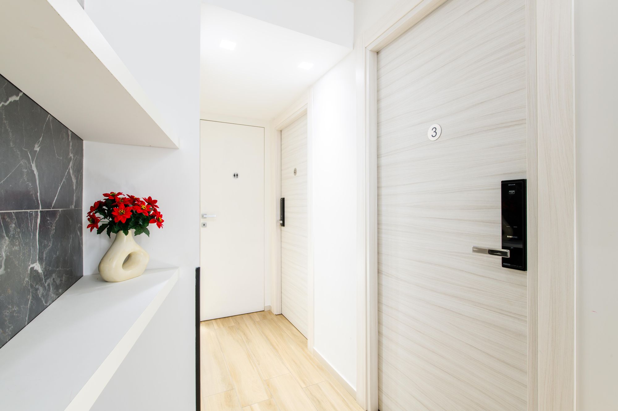 Corridoio con porta della camera numero 3, serratura elettronica e fiori decorativi, Napoli centro