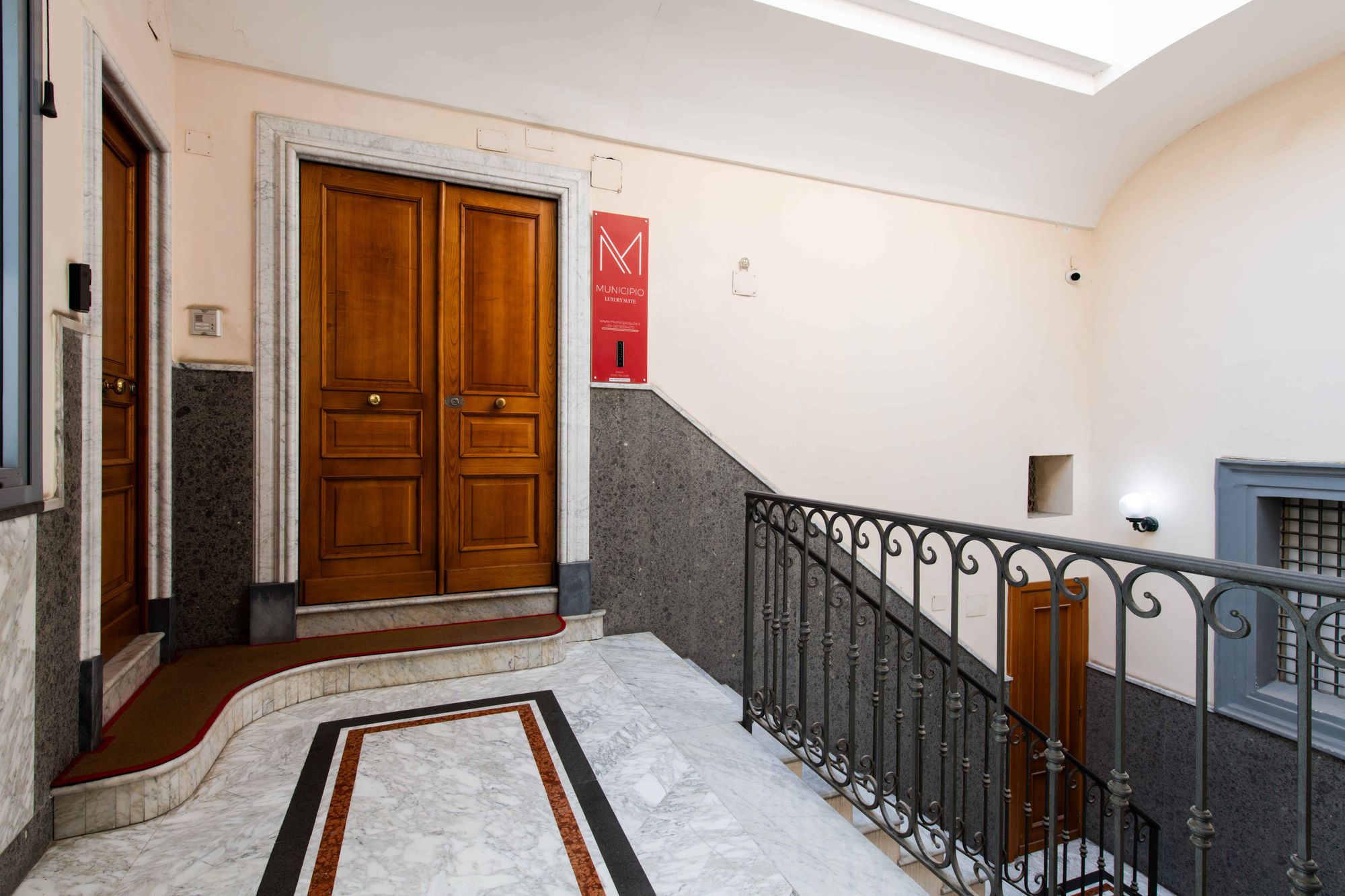 Porte d'ingresso in legno con pavimento in marmo e ringhiera in ferro battuto, palazzo storico Napoli centro